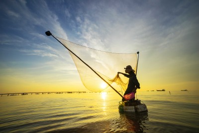 Pêcheur indonésien  jetant son filet au coucher du soleil