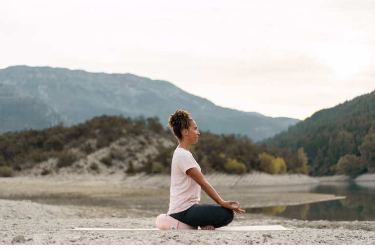 Femme assise au bord d'une rivière pour faire de la méditation