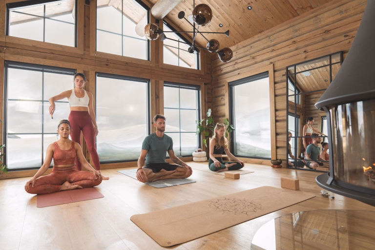 Groupe assis dans un chalet à la montagne pendant un cours de yoga sur la méditation