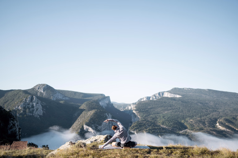 Femme faisant du yoga au sommet d'une montagne