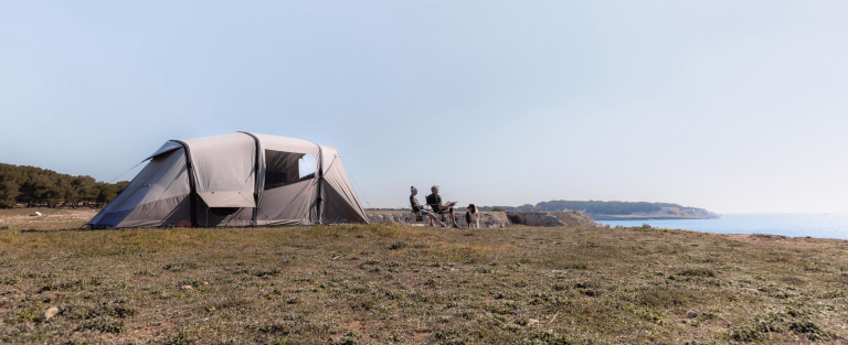tente sur la falaise avec deux personnes qui regardent l'horizon