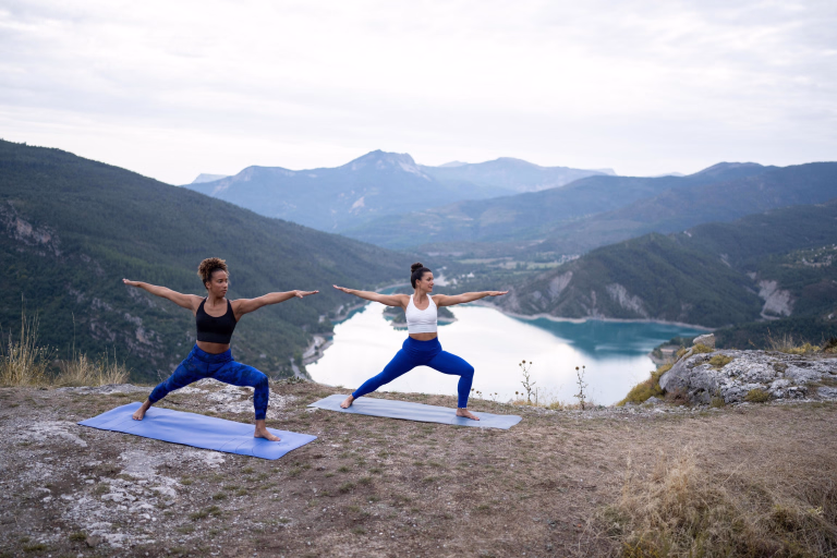 Femmes en posture du yoga en exterieur avec un lac en fond