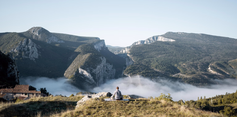 Femme faisant du yoga au sommet d'une montagne
