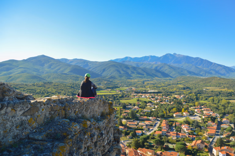 femme assise sur une falaise contemplant la campagne du gers et la ville de lupiac