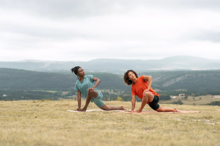 Deux personnes entrain de faire une séance de yoga dans un champ