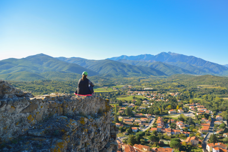 femme assise sur une falaise contemplant la campagne occitane et les montagnes d'occitanie
