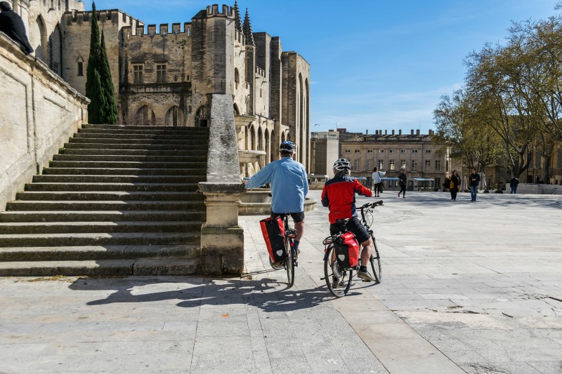 Deux personnes sur les vélos devant la place centrale d'Avignon en Provence